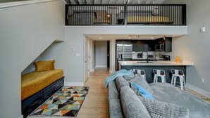 Un appartement en duplex avec une chambre en mezzanine, une kitchenette et un coin repas.