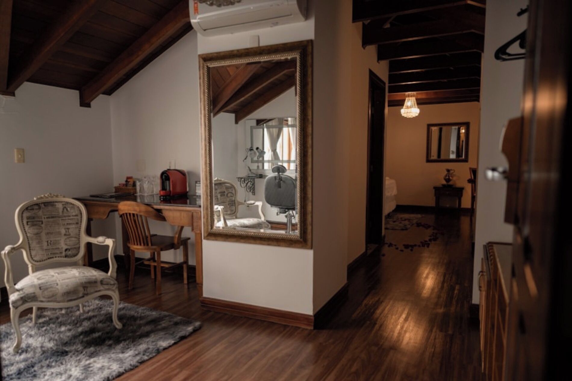 Une pièce avec un plafond en bois, un grand miroir, un bureau avec une chaise et un tapis.