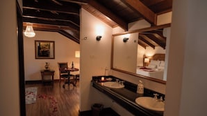 A hotel bathroom with two sinks, a large mirror, wooden beams on the ceiling, and a dining area visible through an open door. - Celebrate Love in Style—Bridal Suite with Breakfast Buffet in Curitiba’s Spot (State of Paraná)