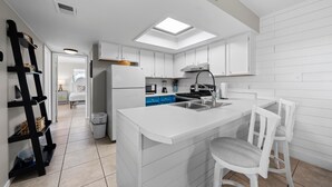 Una cocina moderna con armarios blancos, una isla central y un tragaluz.