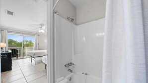Un baño con bañera, ducha e inodoro. Cuenta con un balcón con mesa y sillas.