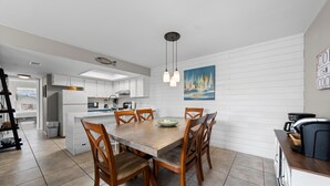 Una cocina moderna con armarios blancos, una mesa de comedor de madera y una isla central.