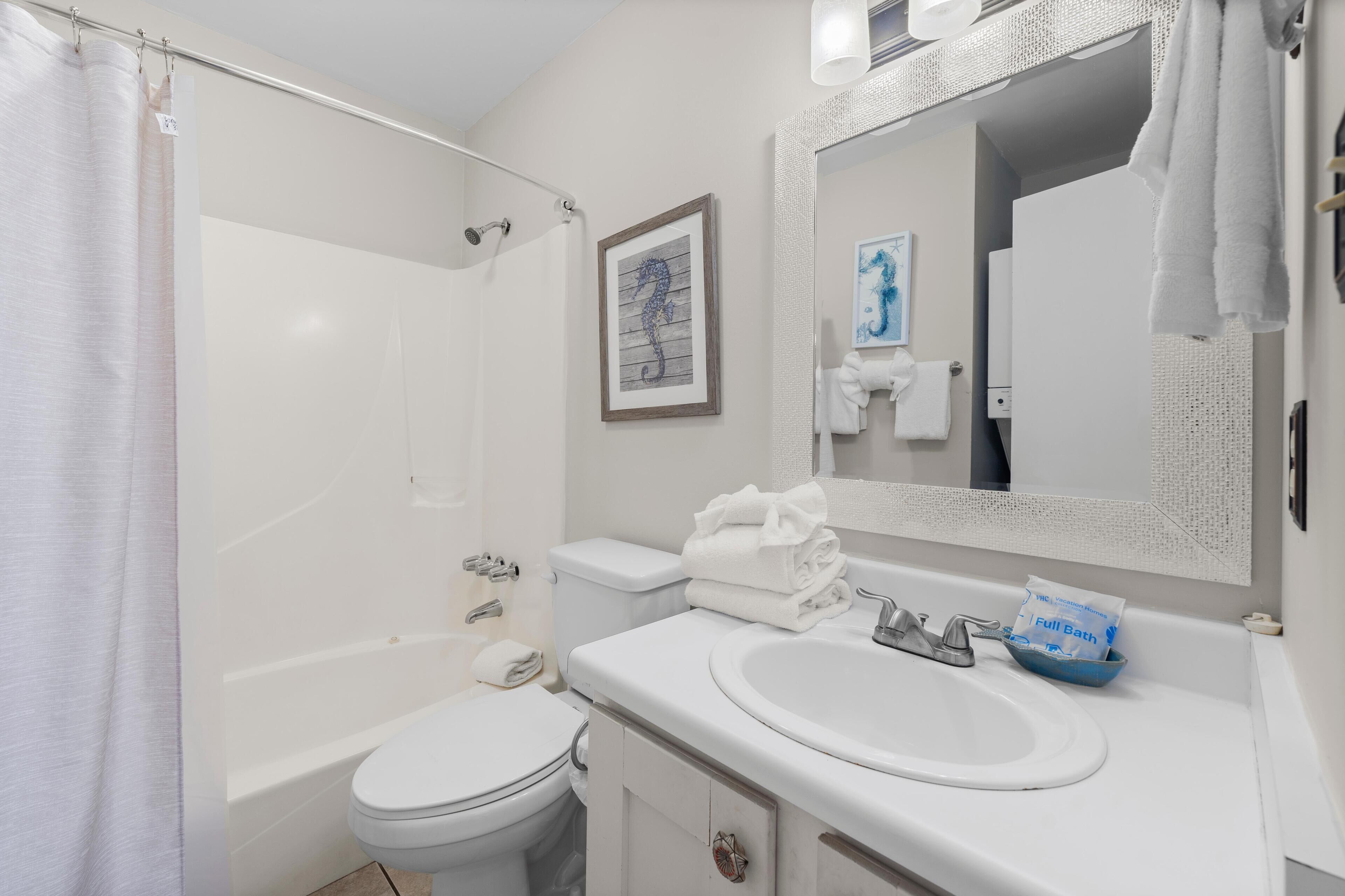 Un baño con bañera, inodoro, lavabo y espejo.