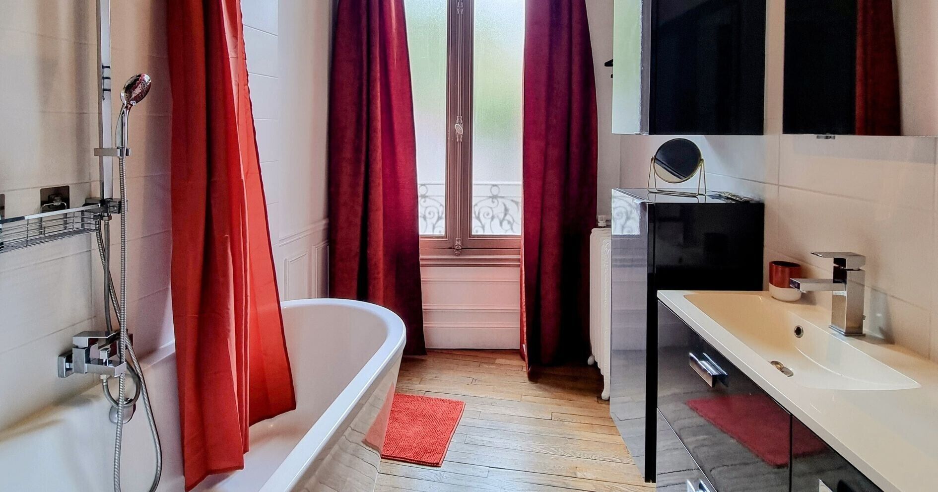 A bathroom with a bathtub, a sink, a mirror, and a window with curtains.
