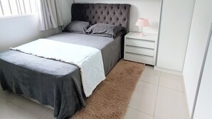 A bedroom with a bed, a nightstand, a lamp, and a fluffy rug. - Complete House in Foz do Iguaçu/PR/Brazil - Sleeps 5 (Foz do Iguaçu)
