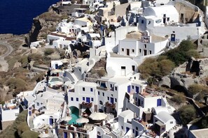 Un pueblo costero con edificios blancos y puertas azules, que muestra una calle estrecha y vistas al mar.