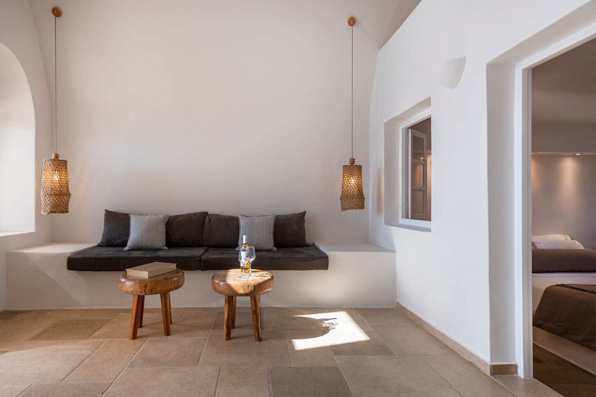 Une pièce moderne dotée d’une banquette intégrée, de deux tables en bois, de lampes suspendues et d’une grande fenêtre.