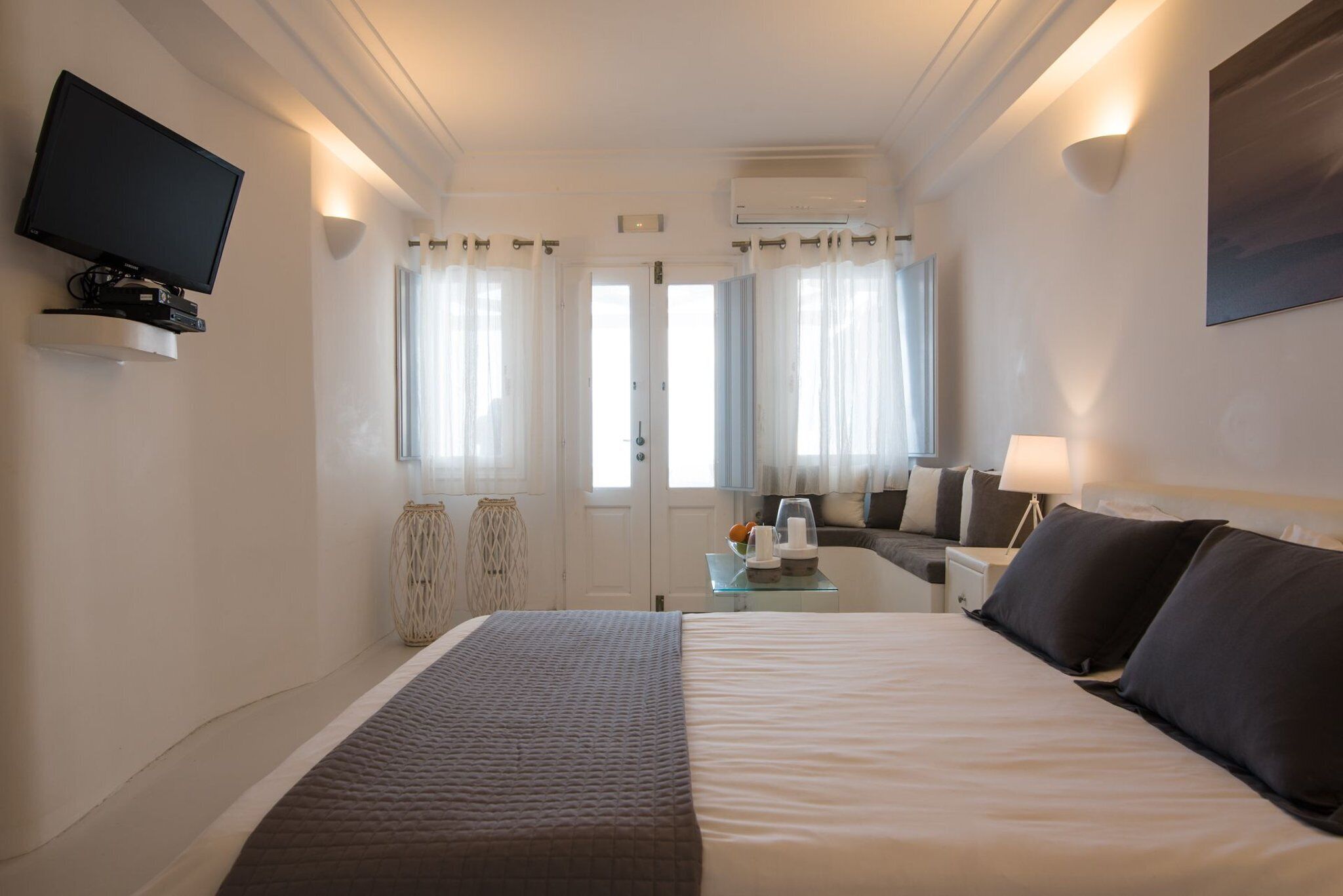 Een hotelkamer met een groot bed, een flatscreen televisie aan de muur, een bureau met een lamp en een raam met gordijnen.