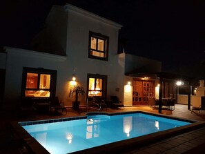 A nighttime view of a house with a swimming pool, featuring a patio area with outdoor seating and a covered dining area. - Villa Marisma | 3 Bedrooms | Private Pool | Prime Location | Furnished Terrace. (Playa Blanca)