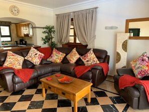 A living room with a brown leather sofa, a wooden coffee table, and patterned cushions. - Villa Marisma | 3 Bedrooms | Private Pool | Prime Location | Furnished Terrace. (Playa Blanca)