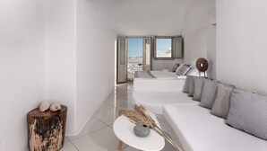 Una habitación de hotel moderna y minimalista con una cama grande, un sofá y una mesita auxiliar.