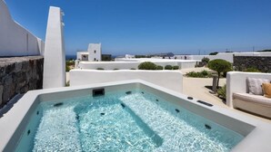 Una piscina en la azotea con agua cristalina, rodeada de edificios blancos y vista al mar.