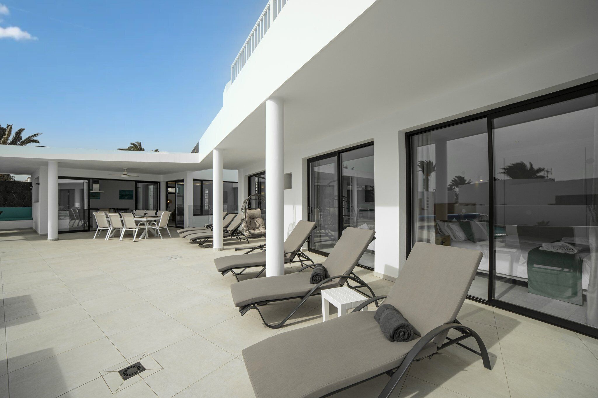 Ein moderner Außenlounge-Bereich mit Liegestühlen, einem Esstisch und Stühlen.