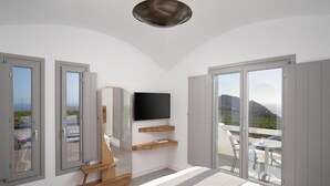 A modern bedroom with a large bed, a TV, and a balcony with a view. - Alluring Santorini Villa | Eruption Escape Villa | Villa with Private Pool &. (Santorini)