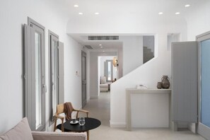 A modern interior with a staircase, a dining area with a table and chairs, and a view of a living space. - Magnificent Santorini Villa | Villa Zephyr Breeze | Family Villa with Private. (Santorini)