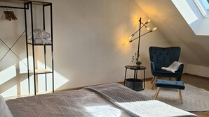 Een moderne slaapkamer met een groot bed, een stoel, een bijzettafeltje en een kledingrek.
