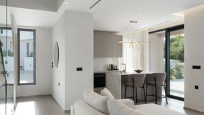 Een moderne keuken met een marmeren aanrecht, een zithoek met twee barkrukken, en een groot raam met uitzicht op de omgeving.