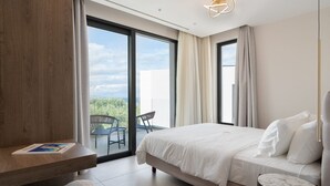 Een moderne hotelkamer met een groot bed, een houten bureau, een klein rond tafeltje en een balkon met een stoel.