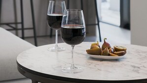 Een moderne eethoek met een ronde marmeren tafel, twee wijnglazen en een schaal fruit.