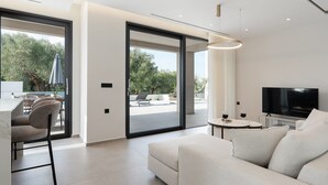 Een moderne woonkamer met een bank, televisie en een eethoek met stoelen en een tafel.