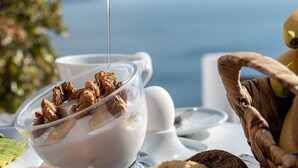 Kirkas lasikulho, joka on täynnä muroja ja maitoa, ja lusikka, jolla kaadetaan lisää maitoa.
