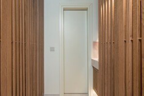 Ein schmaler Korridor mit Holzwandverkleidung an beiden Seiten und einer schlichten weißen Tür am Ende.