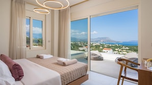 A modern bedroom with a large bed, a desk, and a balcony with a city view. - Elegant Crete Villa | Villa Cretan Soul | 5 Bedrooms | Prviate Pool |. (Crete)