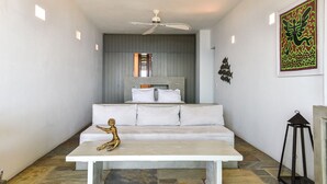 Ein modernes Zimmer mit einem weißen Sofa, einem kleinen Tisch und einem Deckenventilator.
