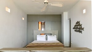Ein modernes Schlafzimmer mit einem in der Mitte des Raumes stehenden Bett, einem Deckenventilator und einer an der Wand befestigten Fischdekoration.