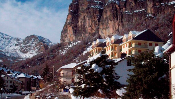 Eine Bergstadt mit schneebedeckten Häusern und einer markanten Klippe.