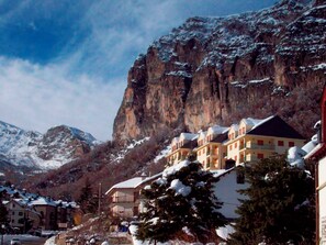Un pueblo de montaña con edificios cubiertos de nieve y un acantilado imponente.