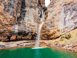 Una formazione rocciosa naturale con una cascata che sfocia in una piscina turchese.