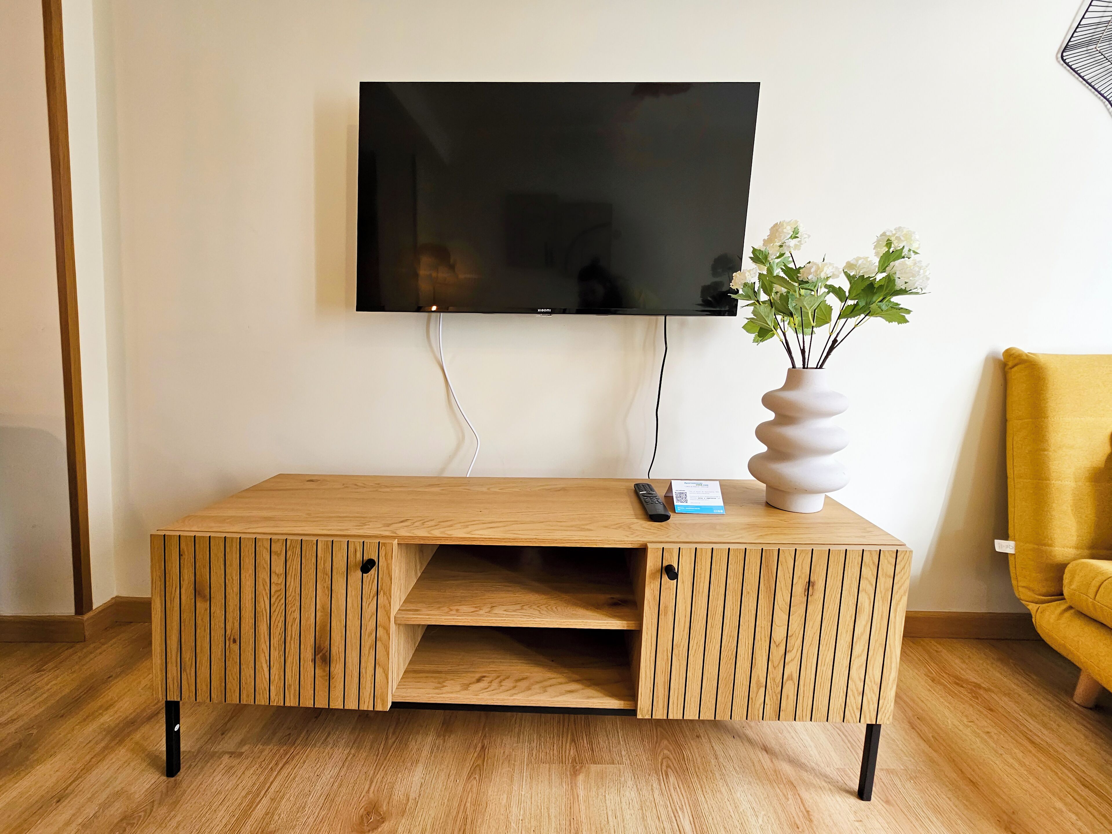 A wooden TV stand with a flat-screen TV mounted on the wall above it.