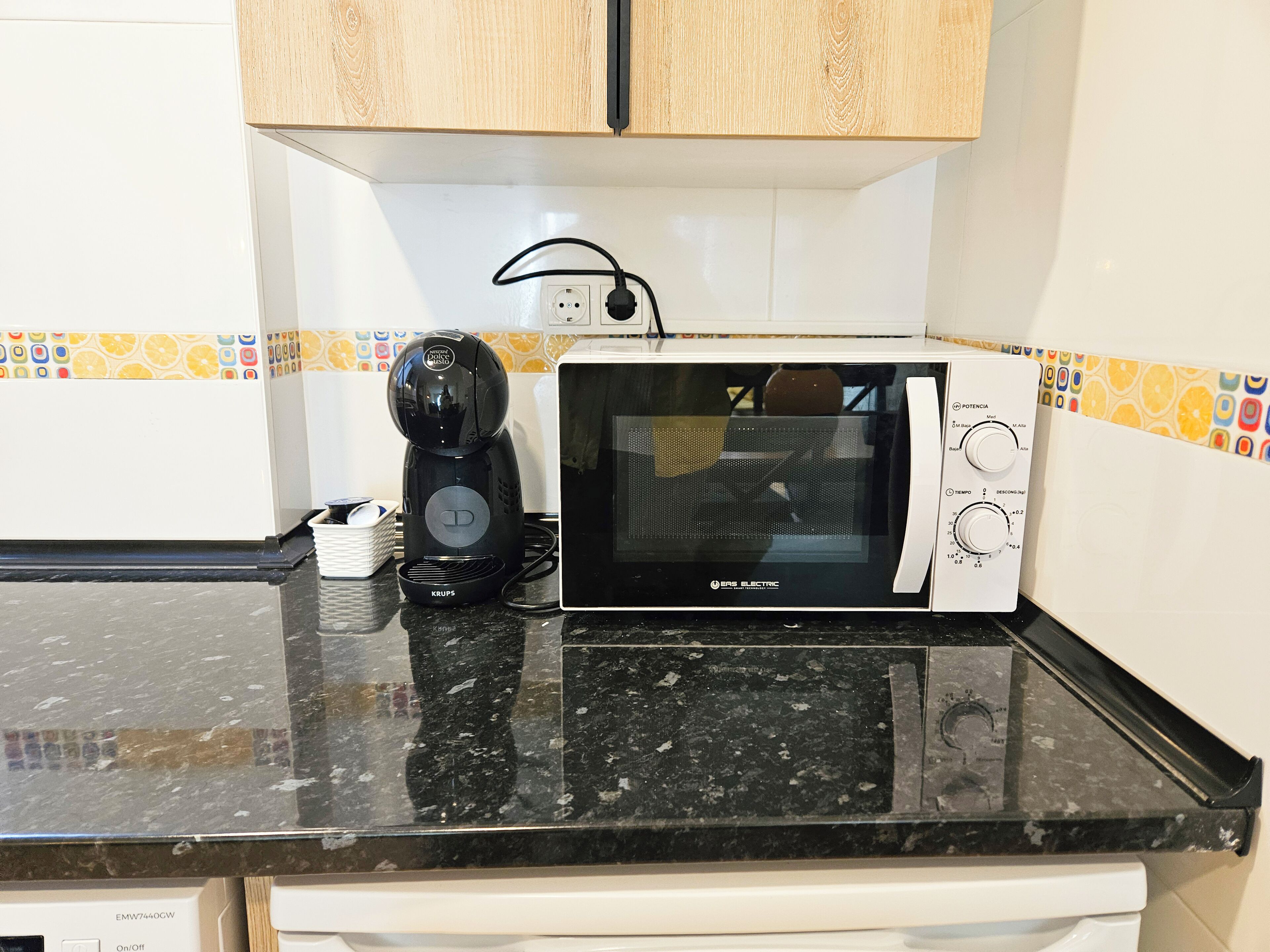 A kitchen with a microwave, a coffee maker, and a white dishwasher.