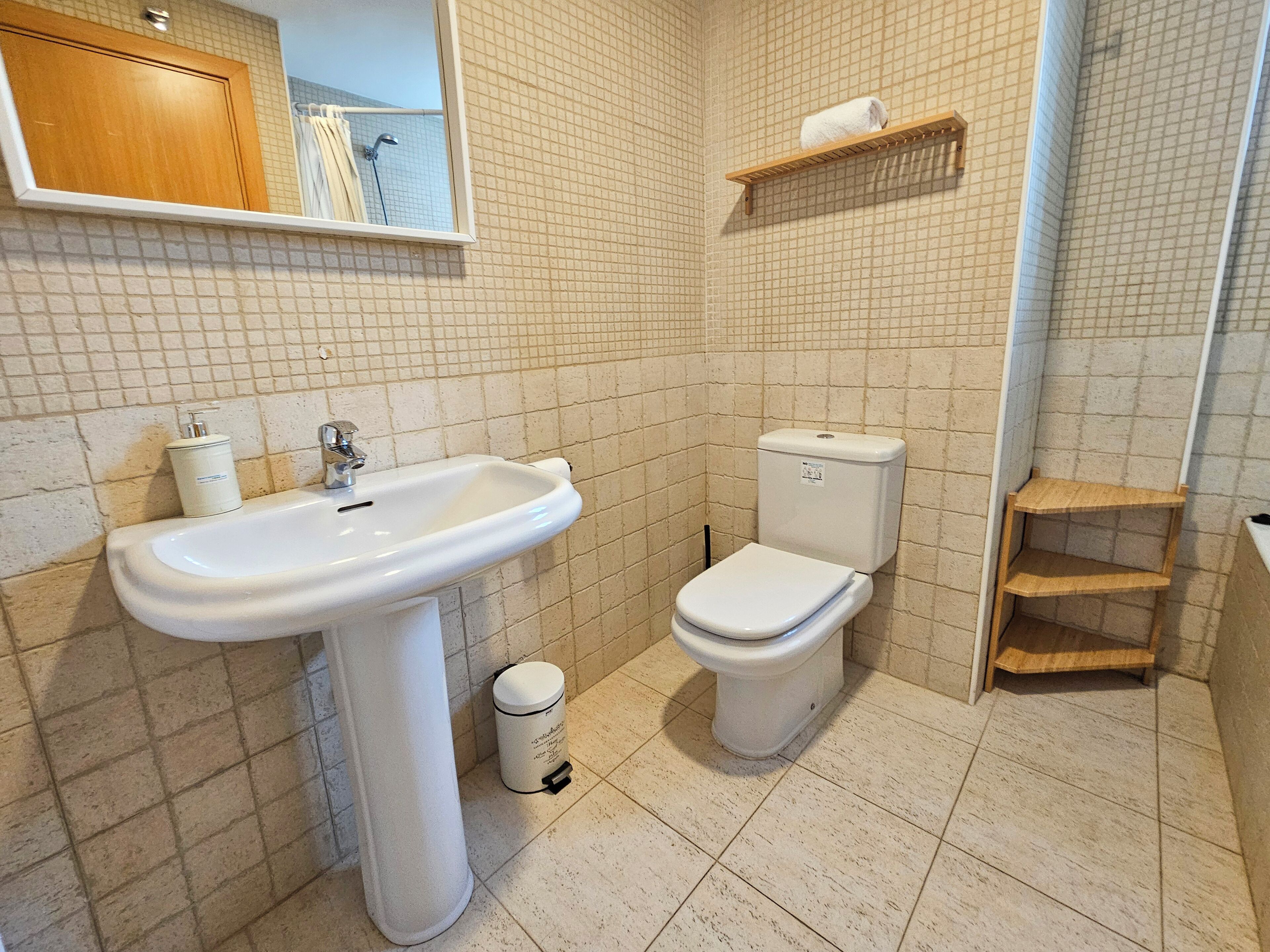 Une salle de bain avec un lavabo, des toilettes et une petite étagère.