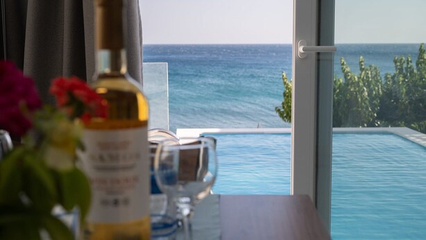 Una habitación con vista al océano, una botella de licor y un vaso sobre una mesa.