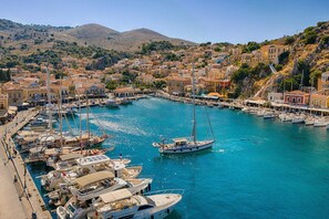 A harbor with numerous boats docked, surrounded by a coastal town with buildings and hills in the background. - Dazzling Symi Villa | Serenity House | 3 Bedrooms | Breathtaking City Views |. (Symi)