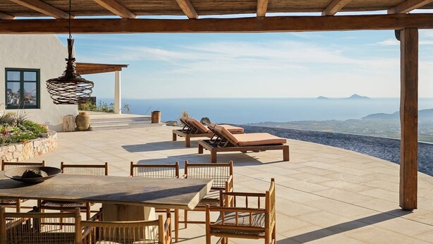 Une terrasse extérieure couverte, aménagée avec une table et des chaises, des fauteuils de relaxation et un luminaire suspendu.