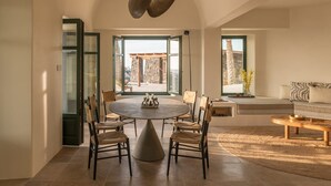 Un vaste espace dédié à la salle à manger, avec une table ronde, des chaises et un luminaire au plafond au design original.