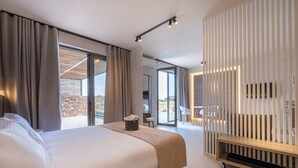 Moderni hotellihuone, jossa on suuri sänky, lasiliukuovi parvekkeelle ja puinen konsolipöytä.