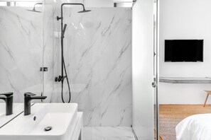 A modern bathroom with a white marble shower, a white sink with two faucets, and a mounted TV on the wall. - Wonderful Athens Villa | Villa Aigai | 7 BDR | Private Balcony and Terrace with. (Athens)