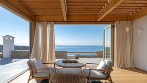 Un balcon agrémenté de meubles en osier, d’une table et offrant une vue sur la mer.