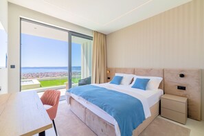 A modern hotel room with a large bed, a desk, and a view of a cityscape through a large window. - Villa Azurea Vista | Trogir-Split | Infinity Pool | Sea Views | Luxury Coastal. (Kastel Stari)
