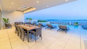Een moderne eetruimte met een panoramisch uitzicht over een kuststad en de oceaan.