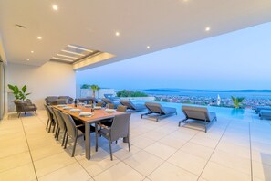 Ein moderner Essbereich mit Panoramablick auf eine Küstenstadt und das Meer.
