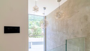 Een modern interieur met een groot raam, geometrische hanglampen en een glazen wand.