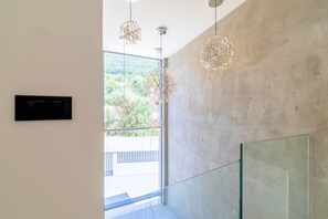 Ein modernes Interieur mit einem großen Fenster, geometrischen Pendelleuchten und einer Glaswand.