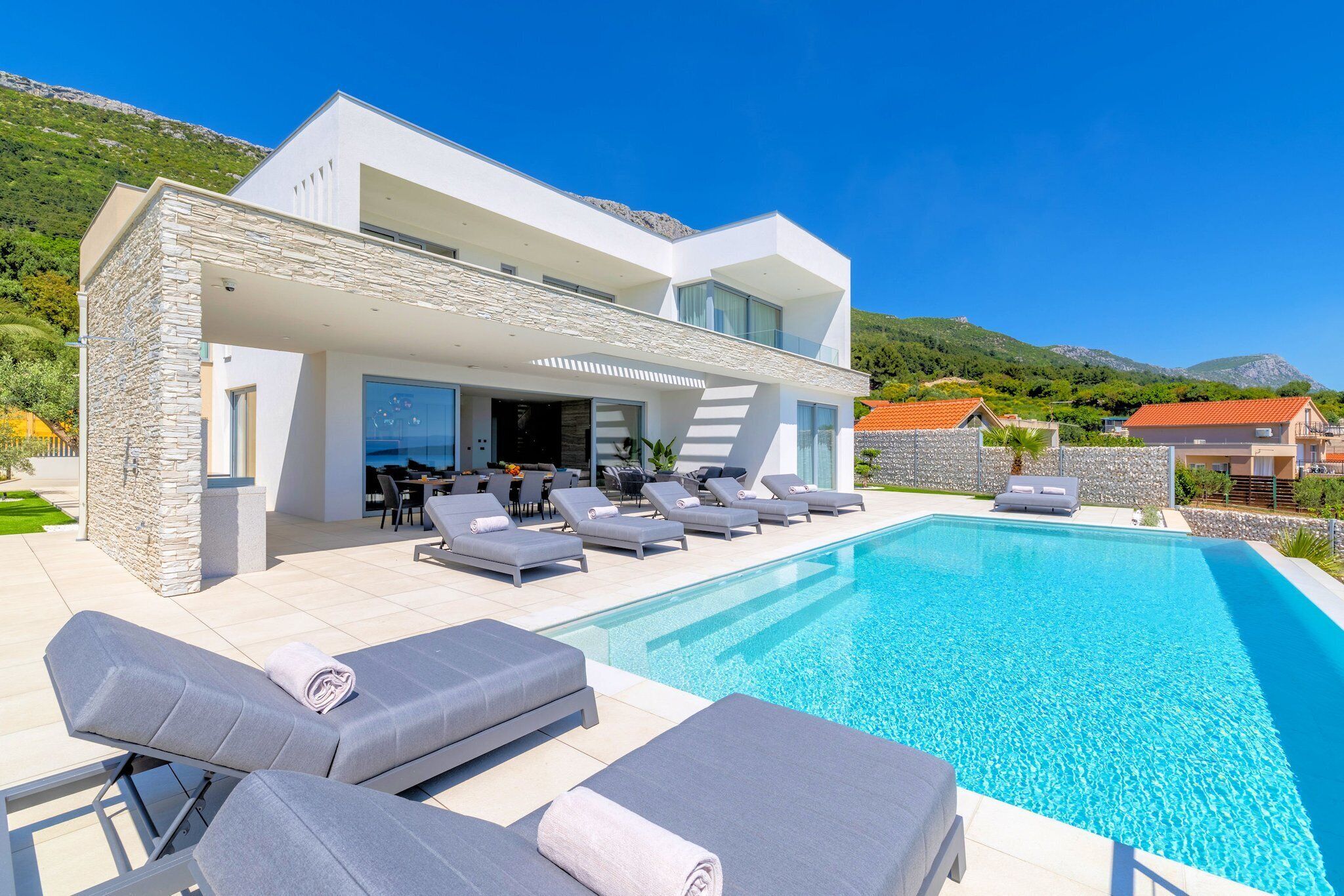 Ein modernes Haus mit Swimmingpool, Sitzgelegenheiten im Freien und Blick auf die Berge.