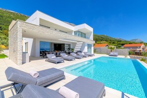 A modern house with a swimming pool, outdoor seating, and a view of the mountains. - Villa Azurea Vista | Trogir-Split | Infinity Pool | Sea Views | Luxury Coastal. (Kastel Stari)