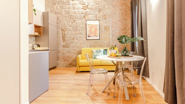 A compact living space with a kitchen, dining area, and a stone wall. - Pina Colada- New apartment in the historic center of Siena (Siena)
